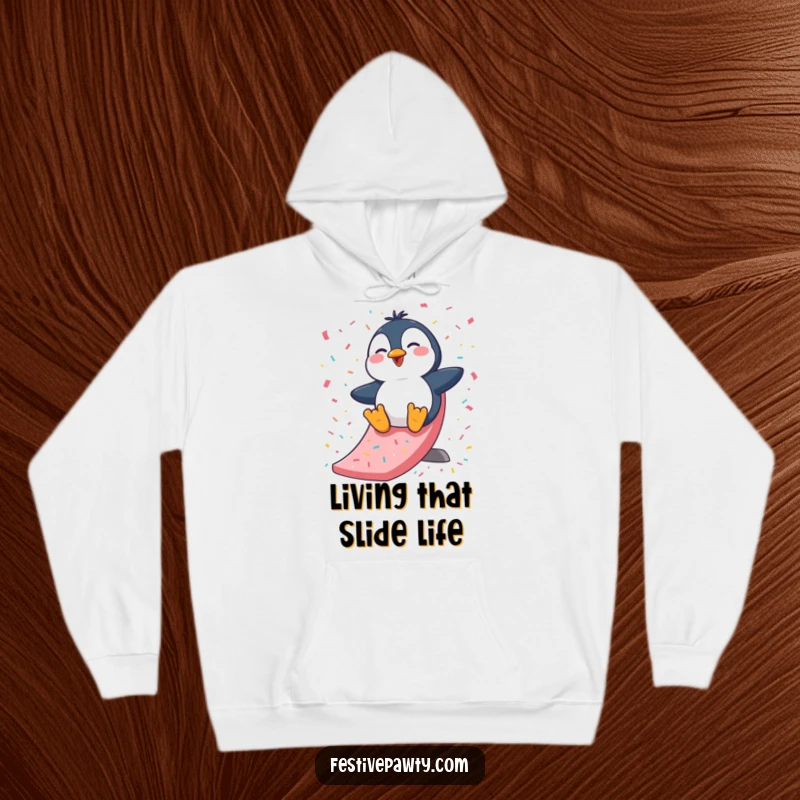 Funny Hoodie: A cute, giggling penguin character slides down a festive confetti slide, radiating warmth and playful energy.