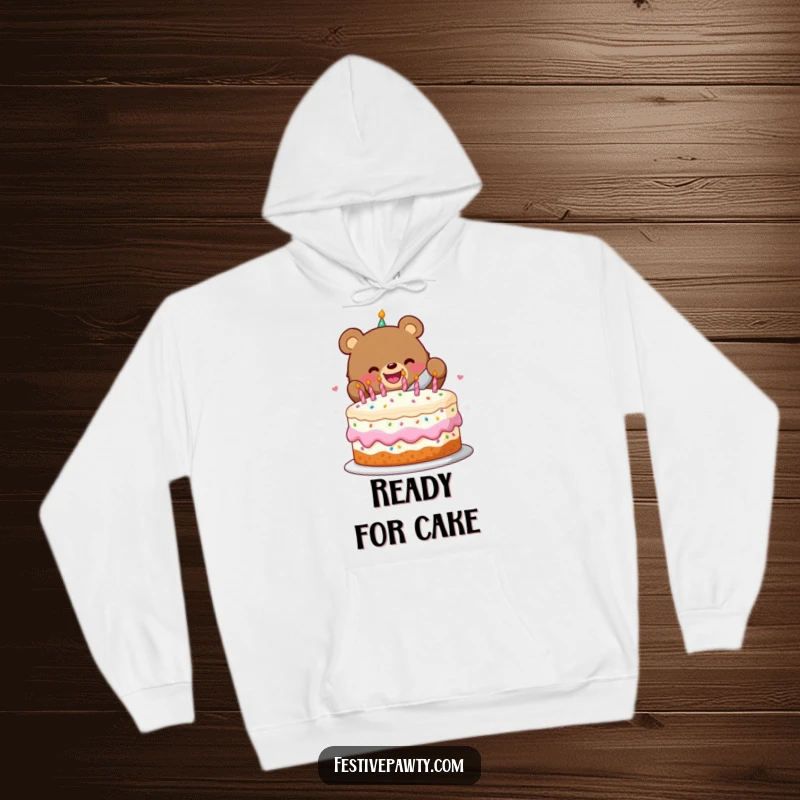 Funny hoodie with a cheerful bear character happily slicing a festive birthday cake, perfect for cozy celebrations.
